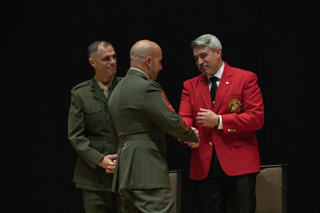 Award recipient, U.S. Marine Corps Gunnery Sgt. Robert Navarro, the officer in charge of the indoor small arms range with Headquarters and Headquarters Squadron, Marine Corps Air Station, and native to Oceanside, California, shakes hands with Rob Brooks, national director of events with the Marine Corps League, during the Gunnery St. Carlos N. Hathcock II award ceremony at MCAS Iwakuni, Japan, Nov. 4, 2025. Gunnery Sgt. Navarro was awarded the Gunnery Sgt. Carlos N, Hathcock II award for his prestigious work and dedication to improving marksmanship of the ISAR and efficiently training rifle and pistol qualifications. (U.S. Marine Corps photo by Lance Cpl. Siwan Lewis)