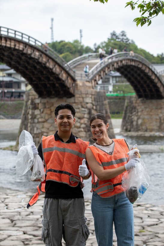 U.S. Marine Corps Sgt. Christian Lim, left, the food service manager for southside mess hall, and Cpl. Amanda Moreno, a food service specialist, both with Headquarters & Headquarters Squadron, Marine Corps Air Station Iwakuni, and natives of Florida, pose for a photo with trash they collected during a clean-up at the Kintaikyo Bridge, Iwakuni, Japan, April 21, 2025. The Marine Corps Community Services Iwakuni, Single Marine Program hosted a bridge clean-up as part of the SMP Days of Service, a five-day series of events where service members from Marine Corps Air Station Iwakuni volunteer to build stronger relationships and give back to the community. (U.S. Marine Corps photo by Sgt. Randall Whiteman)