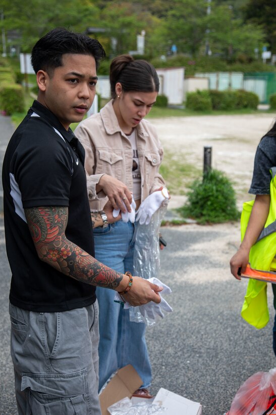 U.S. Marine Corps Sgt. Christian Lim, a food service manager with Headquarters & Headquarters Squadron, Marine Corps Air Station Iwakuni, and a native of Florida, gives gloves to volunteers during a clean-up at the Kintaikyo Bridge, Iwakuni, Japan, April 21, 2025. The Marine Corps Community Services Iwakuni, Single Marine Program hosted a bridge clean-up as part of the SMP Days of Service, a five-day series of events where service members from Marine Corps Air Station Iwakuni volunteer to build stronger relationships and give back to the community. (U.S. Marine Corps photo by Sgt. Randall Whiteman)