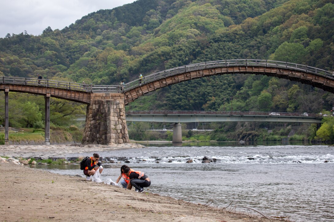 Volunteers from Marine Corps Air Station Iwakuni pick up trash alongside the riverbank during a clean-up at the Kintaikyo Bridge, Iwakuni, Japan, April 21, 2025. The Marine Corps Community Services Iwakuni, Single Marine Program hosted a bridge clean-up as part of the SMP Days of Service, a five-day series of events where service members from Marine Corps Air Station Iwakuni volunteer to build stronger relationships and give back to the community. (U.S. Marine Corps photo by Sgt. Randall Whiteman)