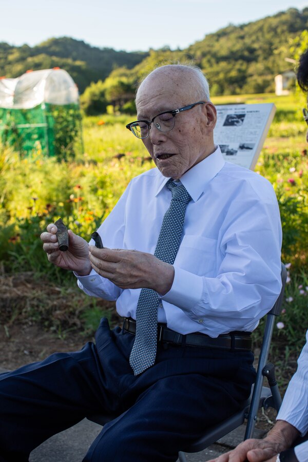 Shigeaki Mori, a Japanese historian and a survivor of the atomic bombing of Hiroshima, shows two .50 Caliber shell casings recovered from a B-24 Liberator during a memorial event, Yanai, Japan, July 28, 2025. Mr. Mori is a prominent historian, and his work was critical in documenting the fate of the Lonesome Lady and her crew. (U.S. Marine Corps photo by Lance Cpl. Micah Taylor)