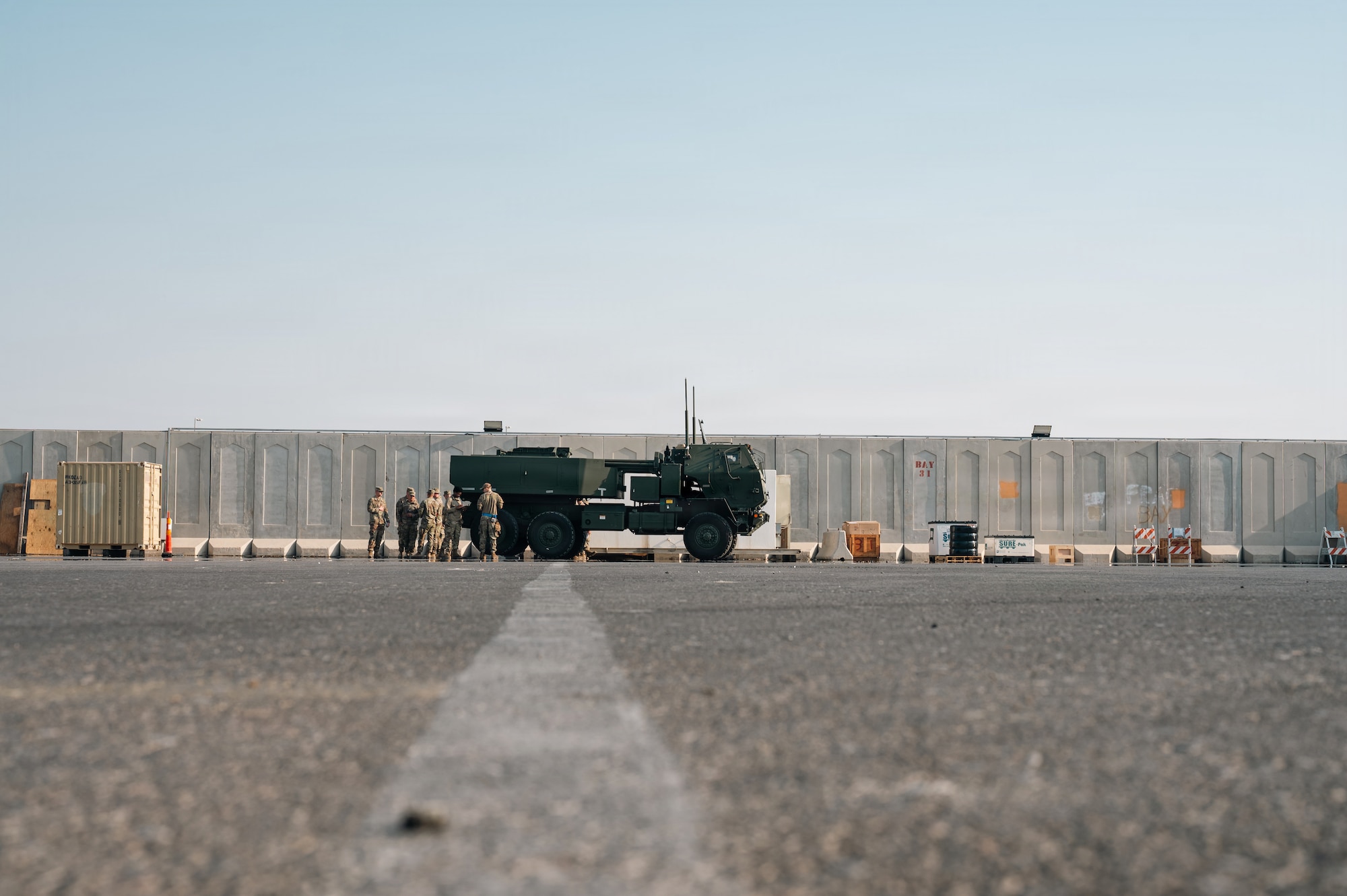 People stand around military vehicle