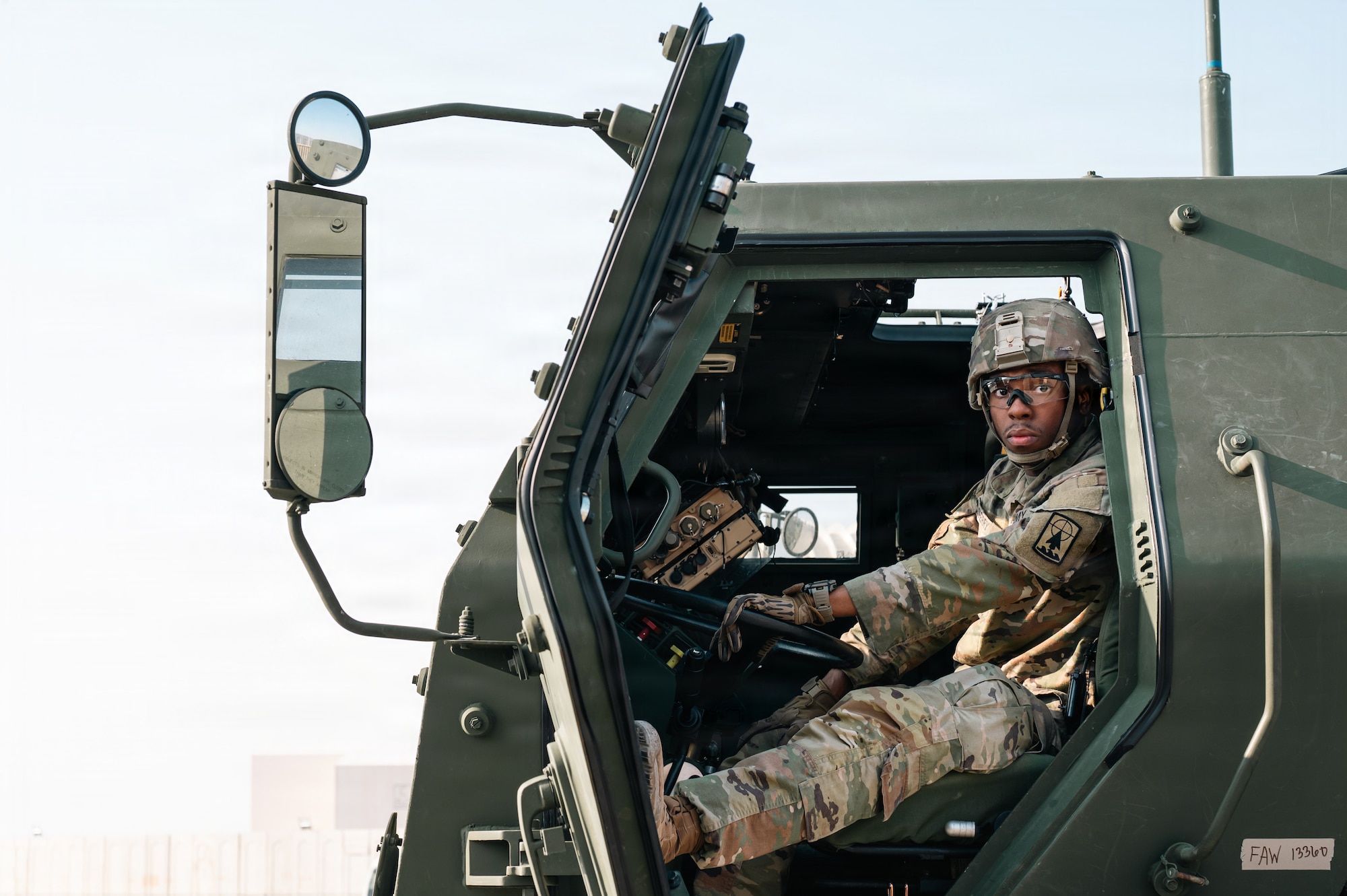 People stand around military vehicle