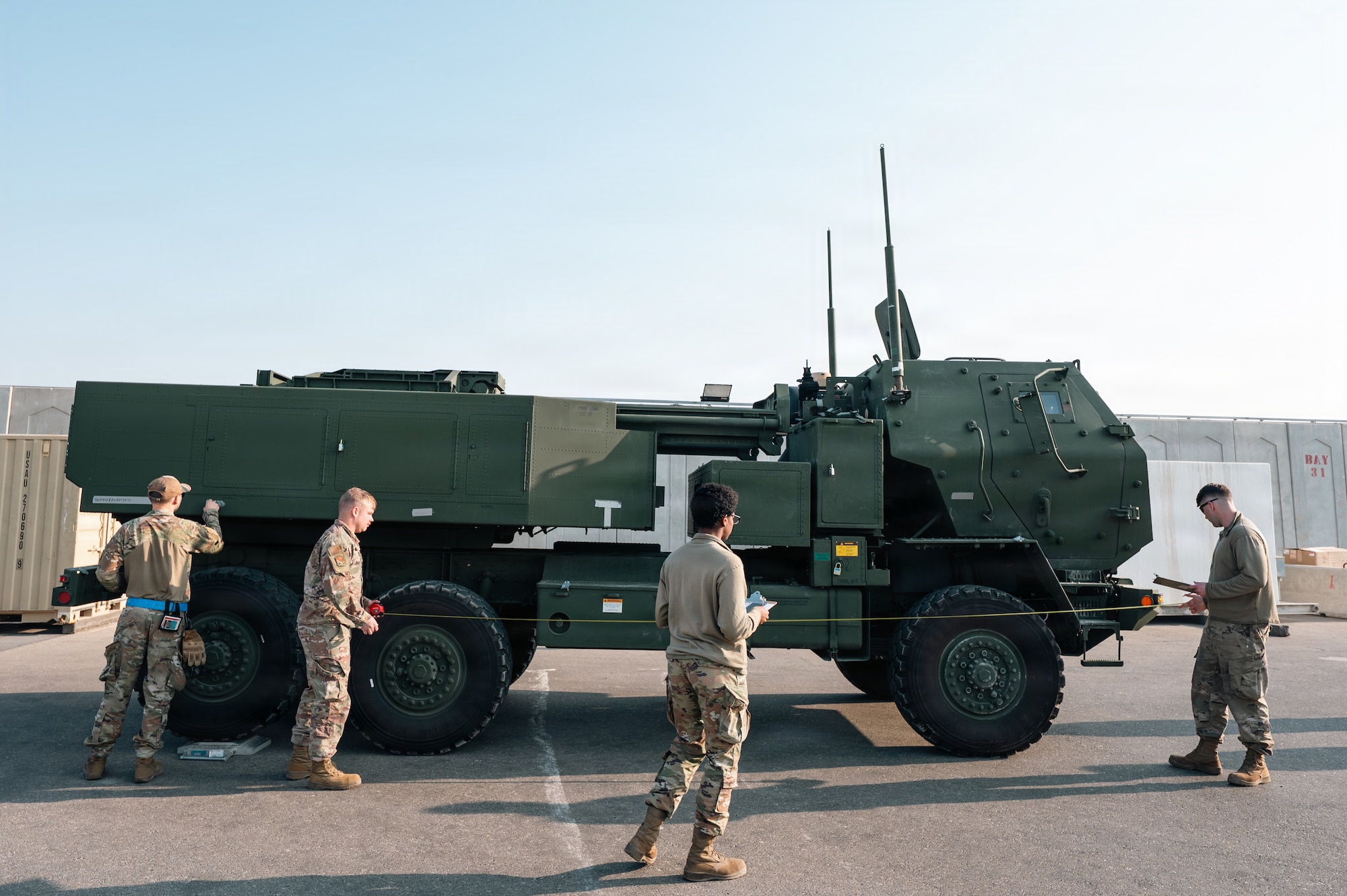 People stand around military vehicle
