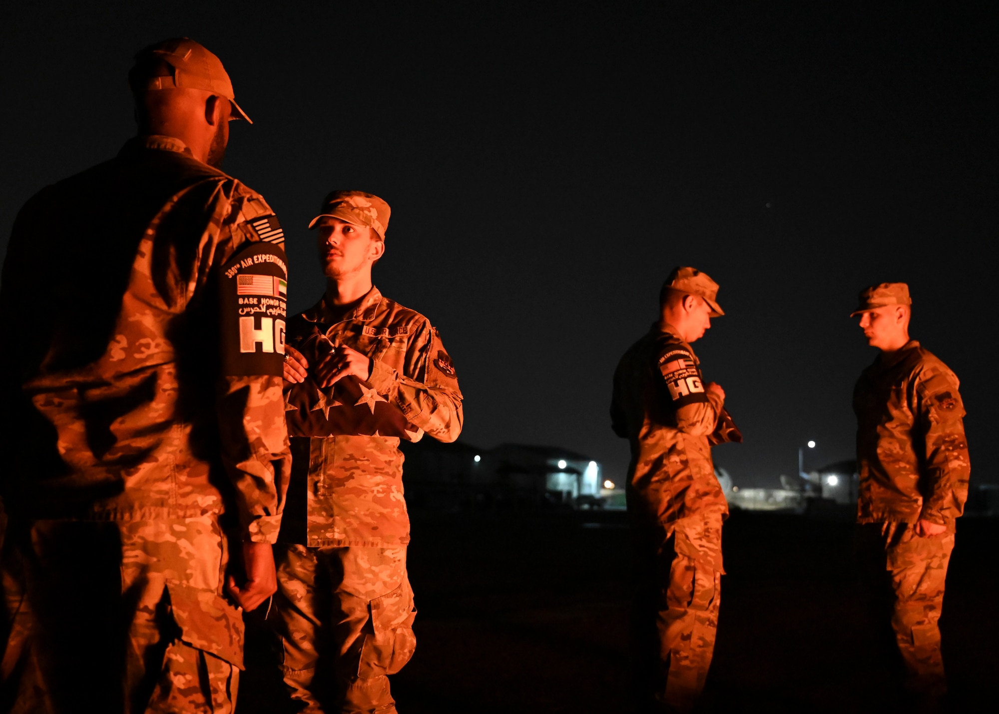 Men in military uniforms unfold flags.