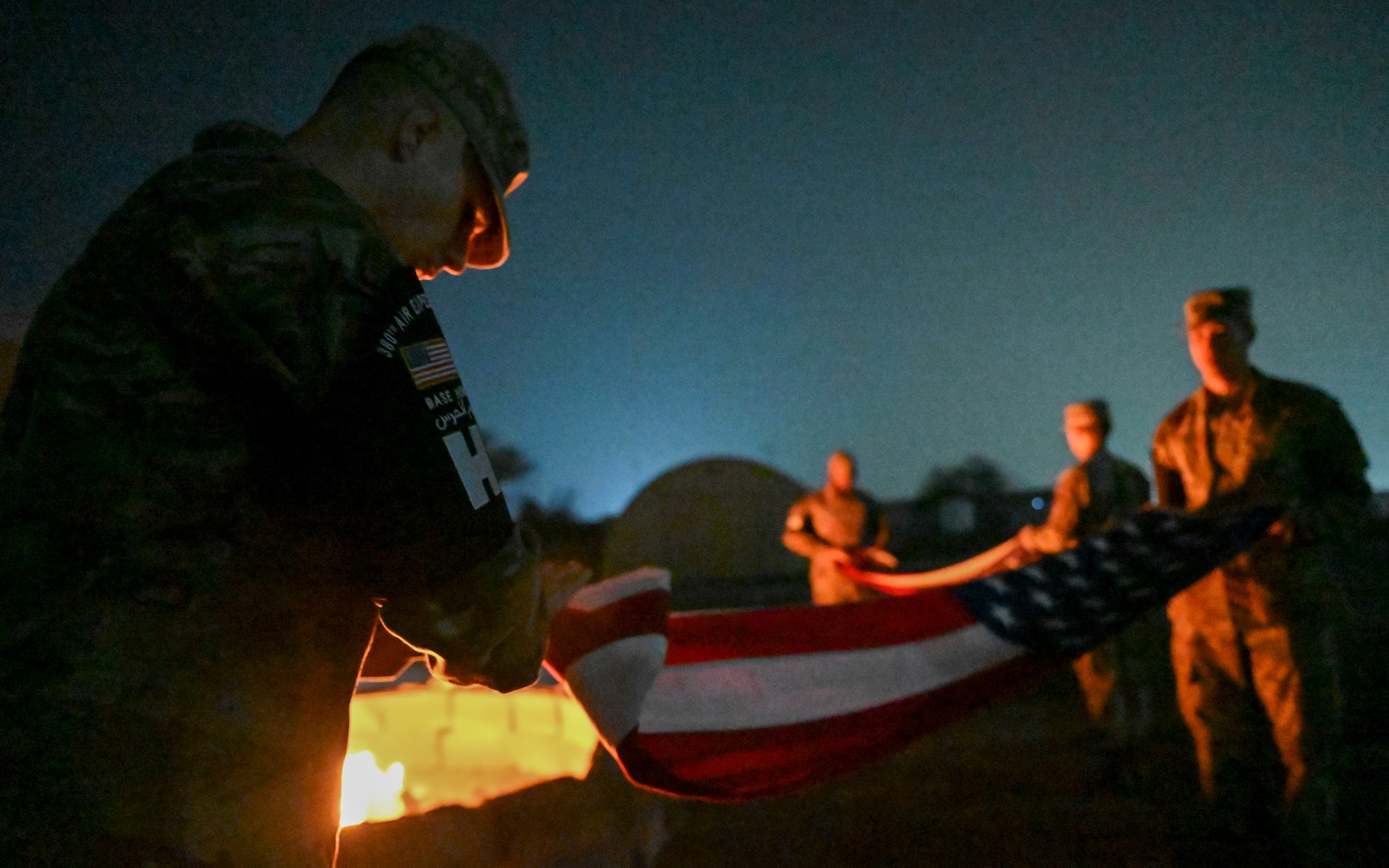 A man in a military uniform folds a flag.