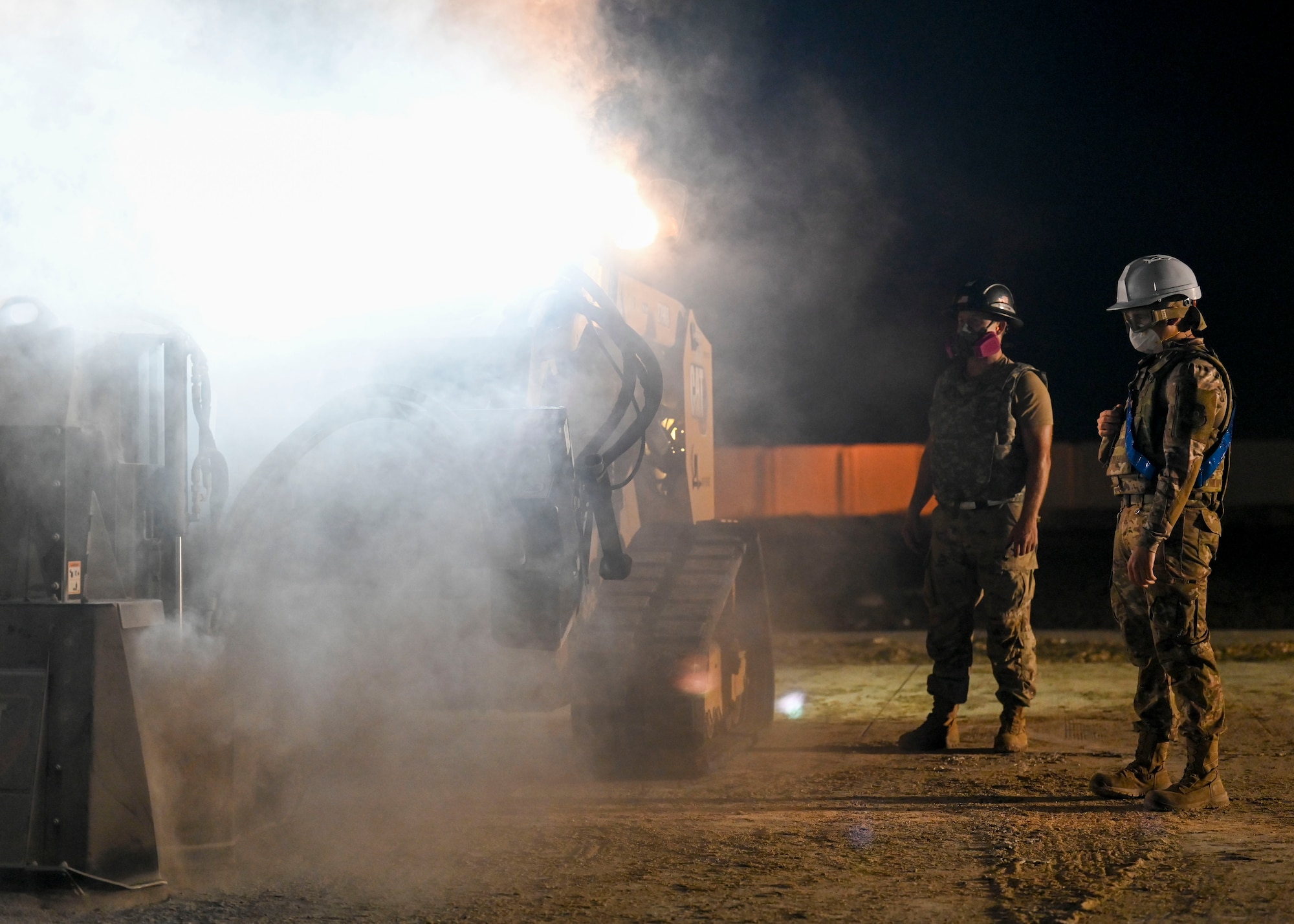 Men in military uniforms watch machine operated saws cut concrete.