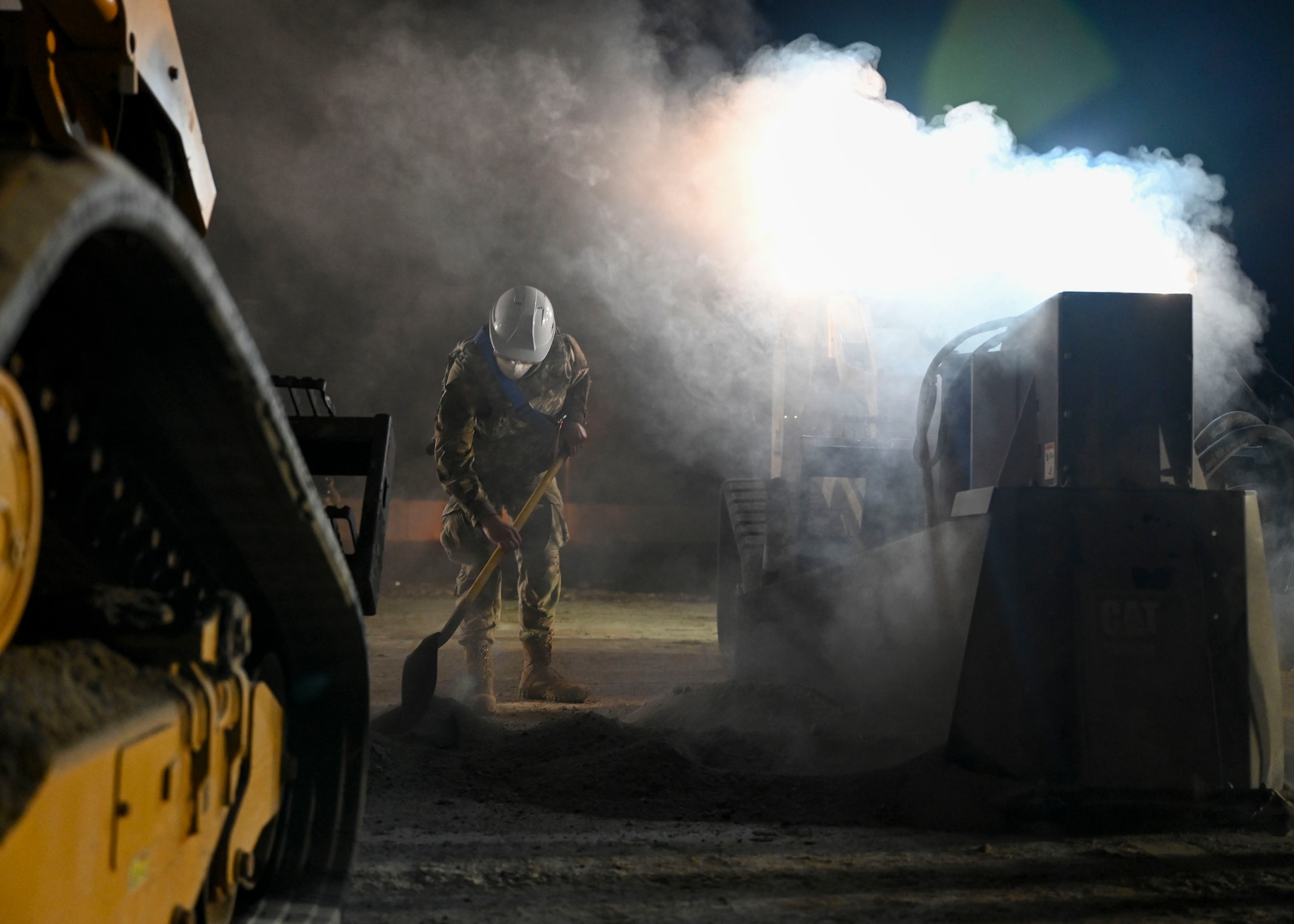 A man in a military uniform clears debris created by concrete saws.