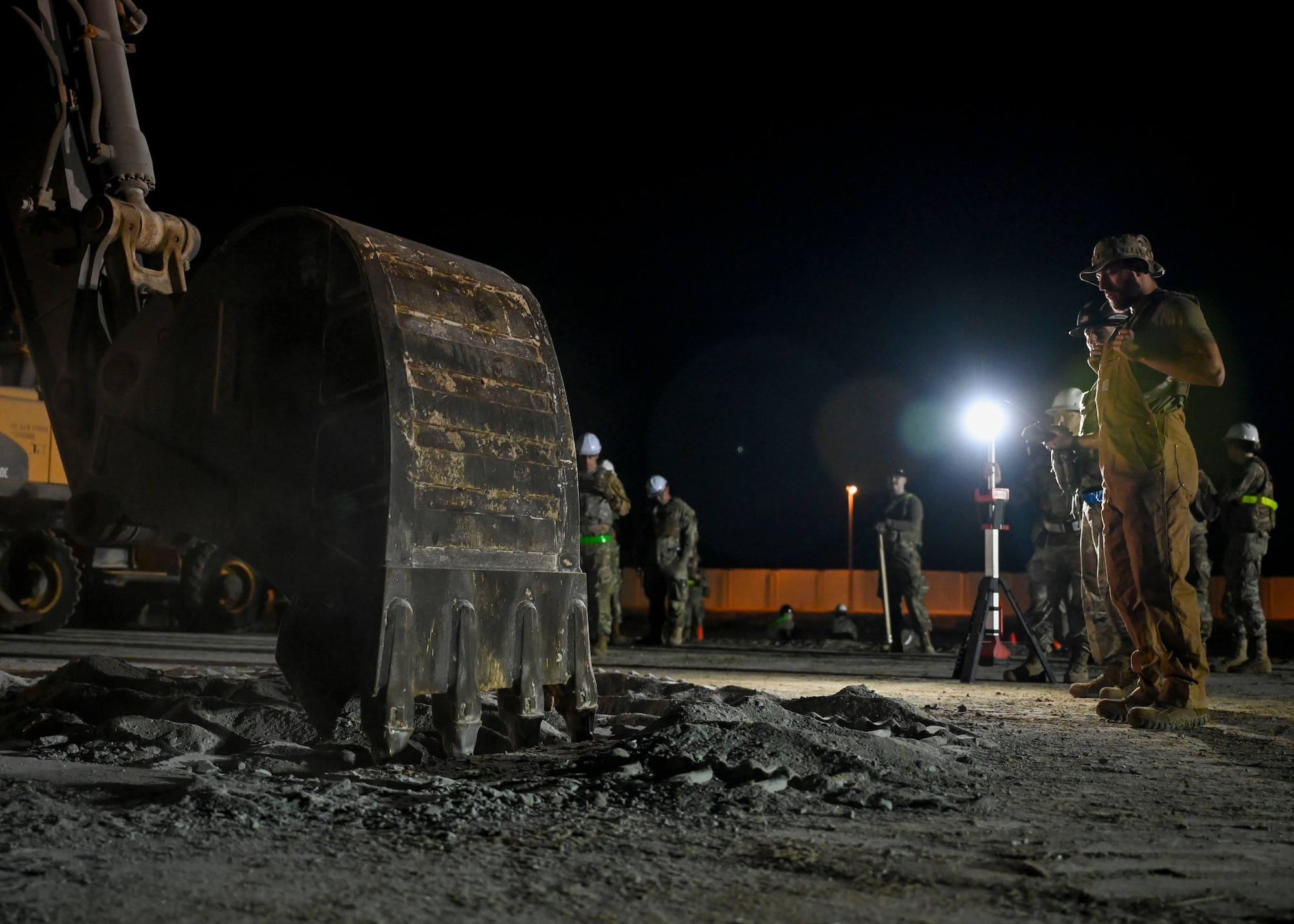 A man watched an excavator dig a hole.