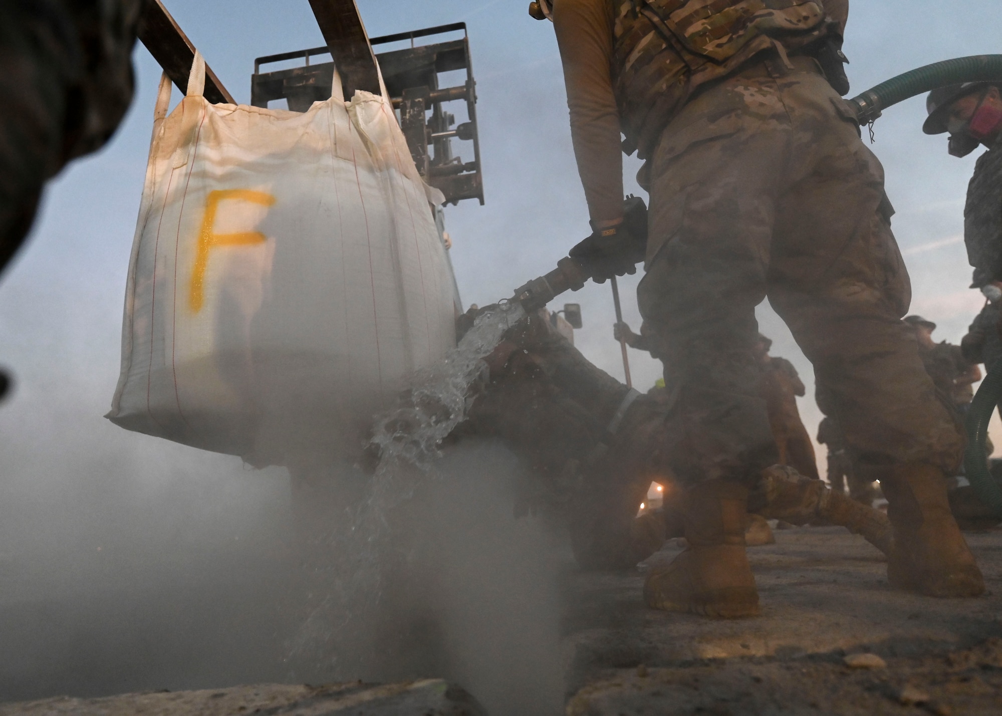 Men in military uniforms mix conrete.