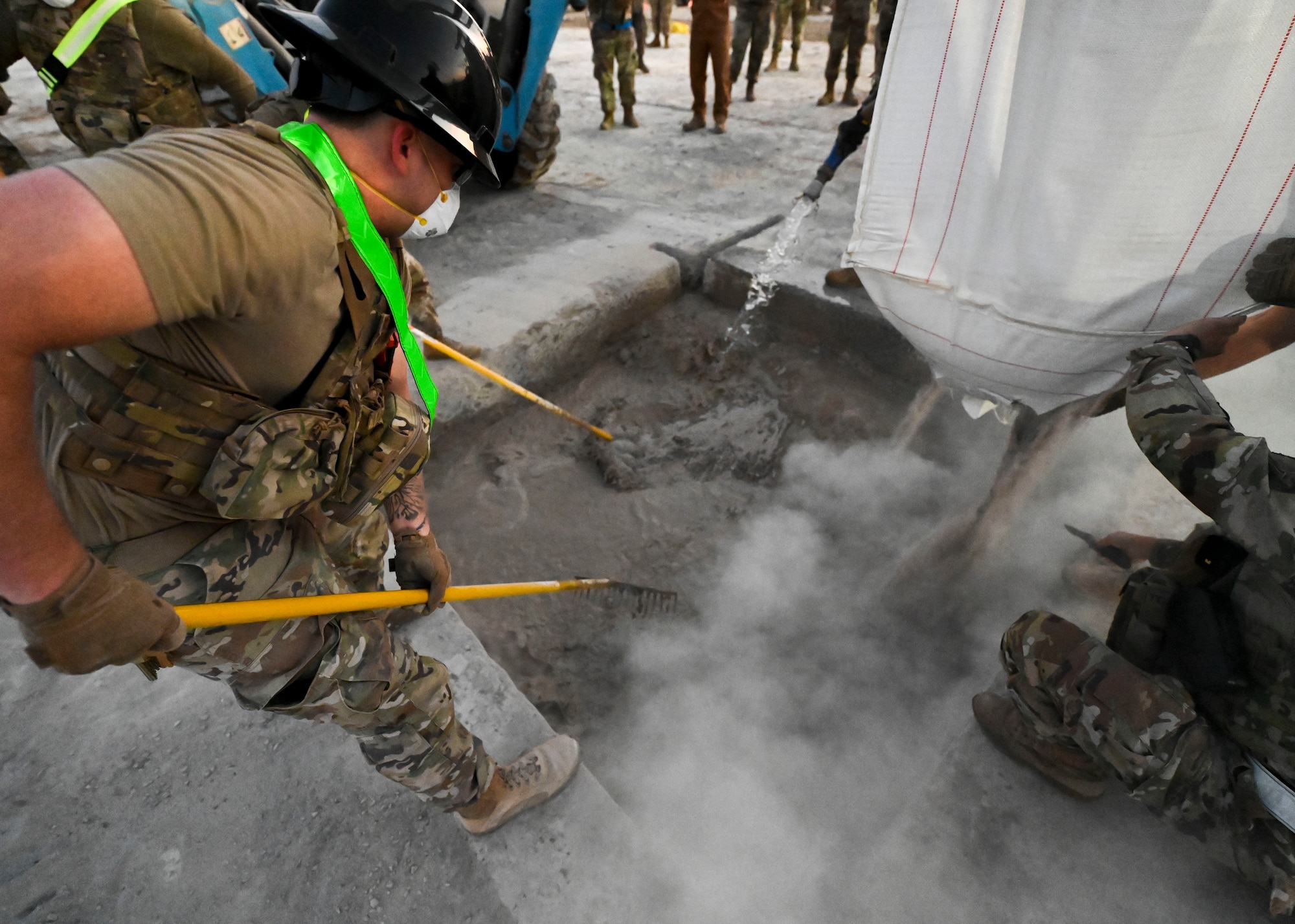 Men in military uniforms mix concrete.