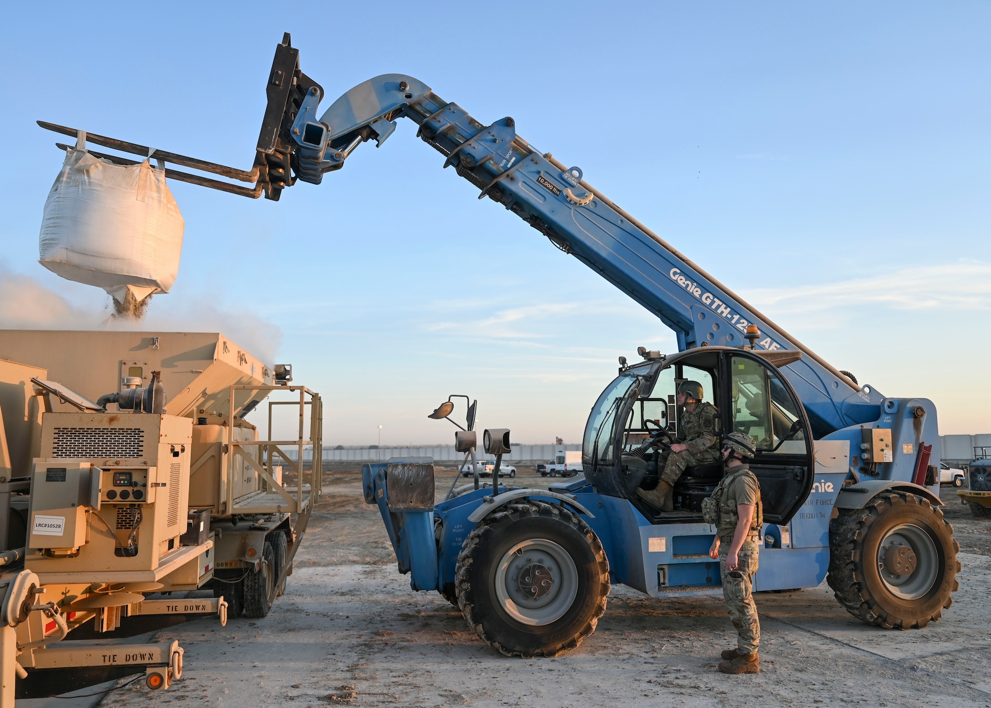 A large forklift lifts a bag of cement mix.