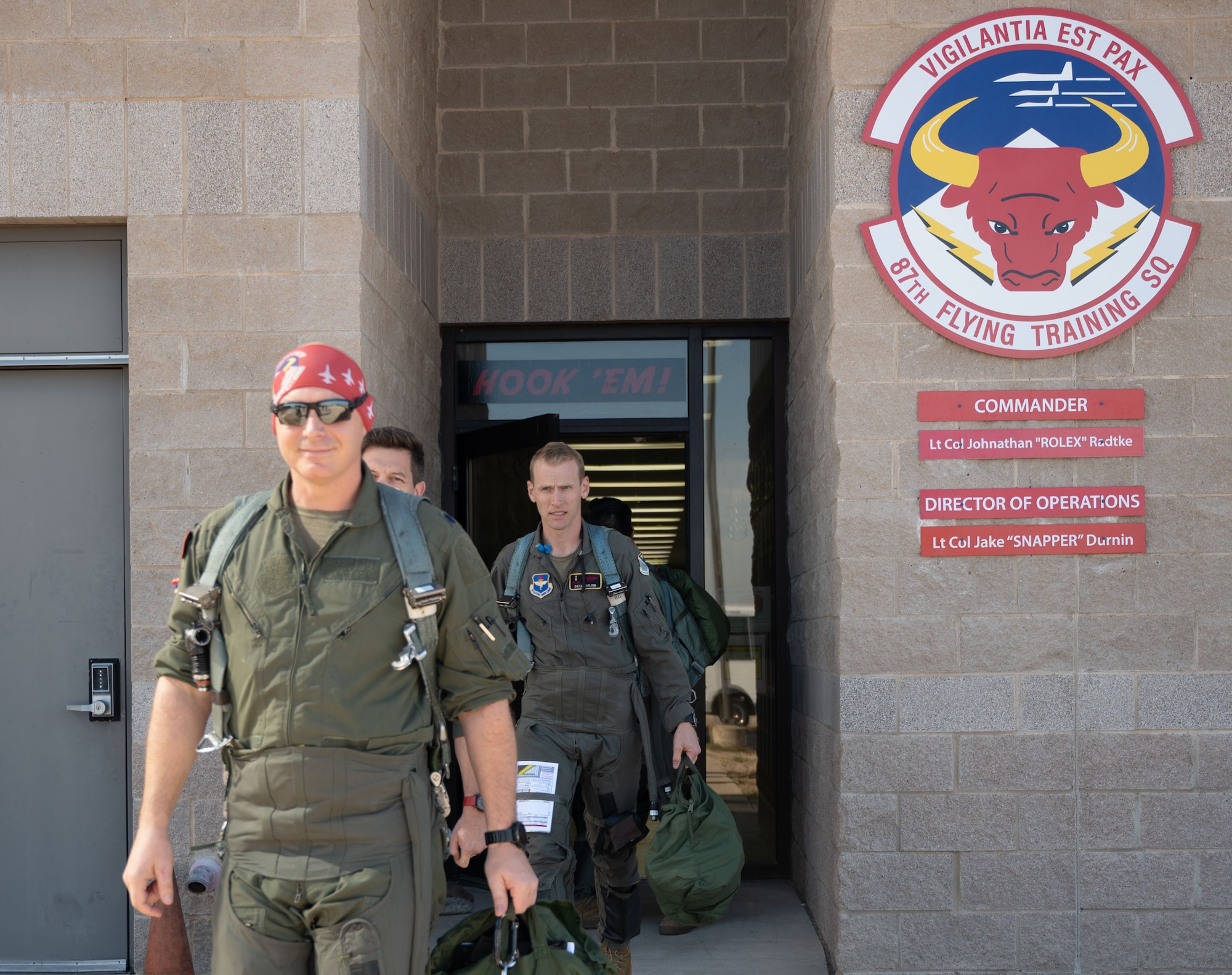 Pilots step out of a building.