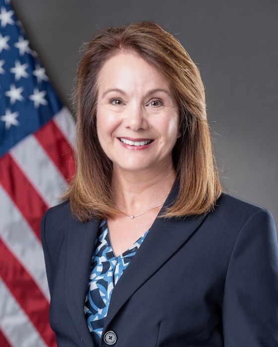Official photo of Ms. Leslie Forrester in front of an American Flag.