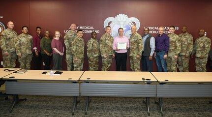 Wally Edwards, center, safety manager for U.S. Army Medical Logistics Command, presents the Army’s Safety Excellence Streamer award for the brigade level to team members at AMLC headquarters Jan. 7, 2026.