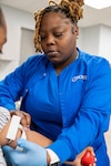 Herlene Alexandre, phlebotomy extern at Miami MEPS, conducts a blood draw on an applicant. USMEPCOM introduced a new medical externship initiative designed to assist with collecting vitals, drawing blood and urine samples and conducting vision and audio screenings.