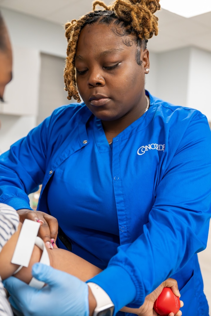 Herlene Alexandre, phlebotomy extern at Miami MEPS, conducts a blood draw on an applicant. USMEPCOM introduced a new medical externship initiative designed to assist with collecting vitals, drawing blood and urine samples and conducting vision and audio screenings.