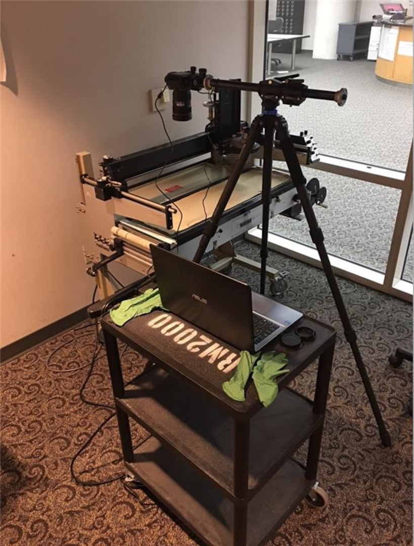 Geospatial analysts utilize a tripod, Canon DSLR camera, laptop, and an antique light table to digitize the archival negatives on Dec. 3, 2025.