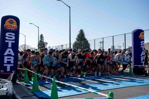 A large group of runners prepare to run across the starting line.