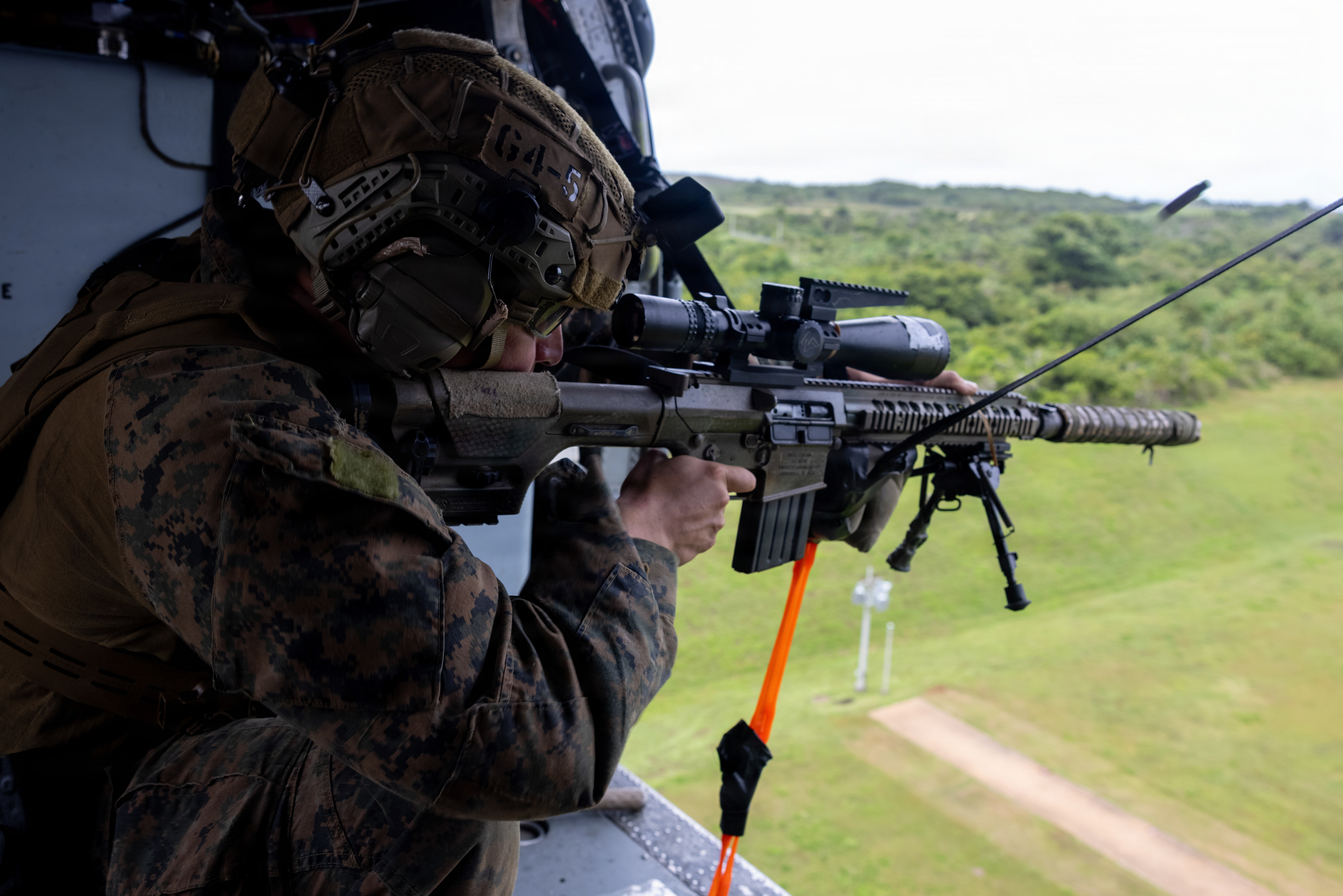 A U.S. Marine with 3rd Reconnaissance Battalion, Maritime Raid Force, 31st Marine Expeditionary Unit, fires a M110 Semi-Automatic Sniper System aboard a MH-60S Seahawk on Mason Range, Marine Corps Base Camp Blaz, Guam, Jan. 13, 2026. Marines utilized Mason Range to conduct aerial sniper training to maintain readiness and lethality among the MEU and reconnaissance force. (U.S. Marine Corps photo by Cpl. Ryan Little)