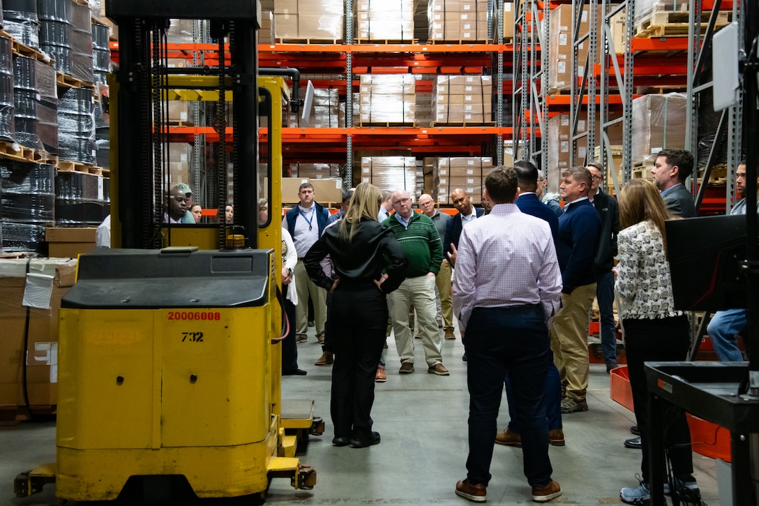 A group of people stand inside a warehouse talking to each other.