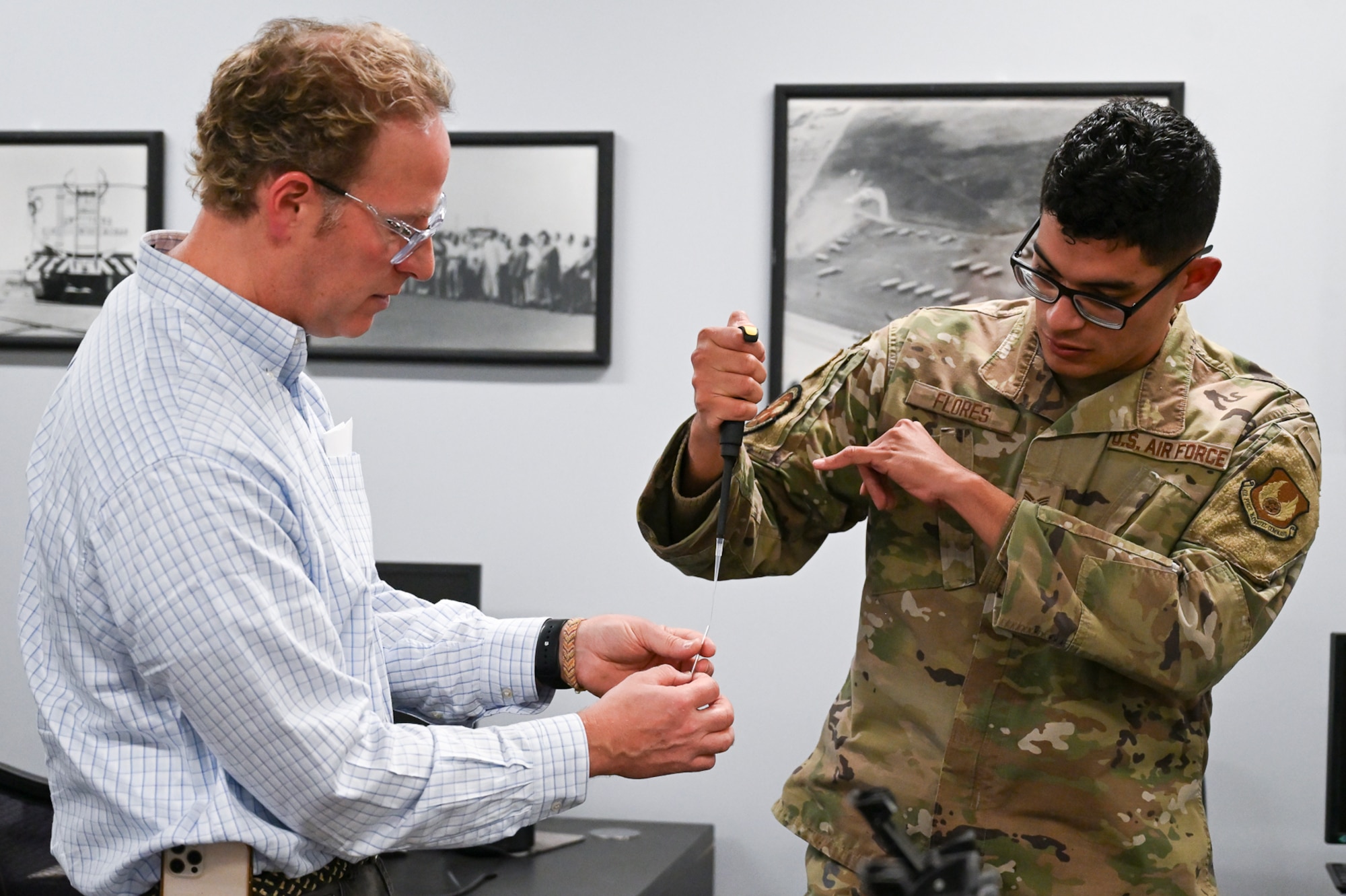 Nelson Stacks, president and CEO of Wave Guide Corporation, explains the operation of a prototype hydraulic fluid testing device to Senior Airman Nathan Flores, 75th Logistics Readiness Squadron fuels flight, Oct. 27, 2025, at Hill Air Force Base, Utah The Air Force Petroleum Office, the single enterprise manager for petroleum and aerospace energy, is partnering with the 75th LRS at Hill Air Force Base to attain a prototype that will significantly reduce the time it takes to test jet fuel for contamination from PAO and aviation-grade hydraulic fluid. (U.S. Air Force photo by 1st Lt. Rachel Shaffer)