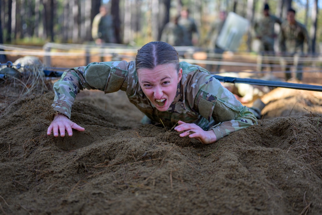 Officer Trainee Viva Kreis crawls through sand for obstacle course.