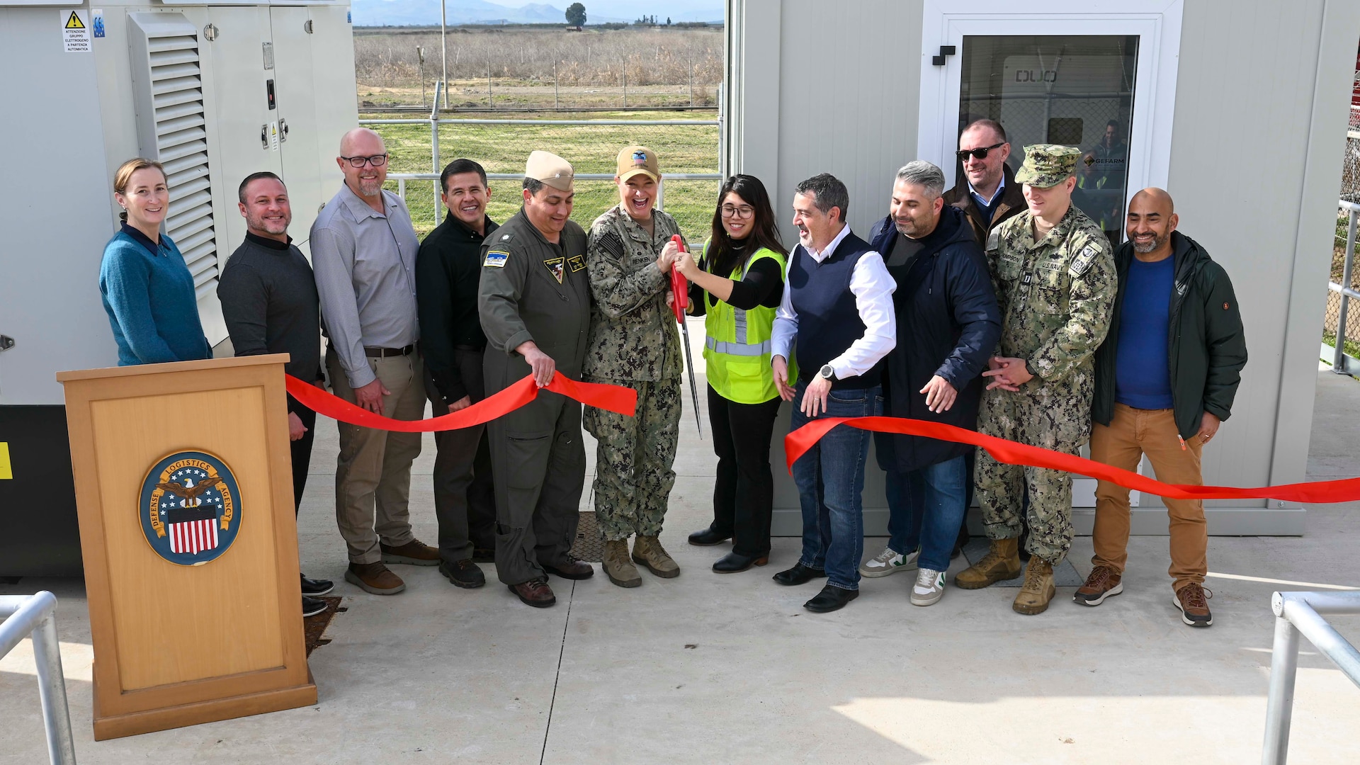 People cutting a ribbon at a ceremony for the Battery Energy Storage System at Defense Logistics Agency Distribution Sigonella, Italy.