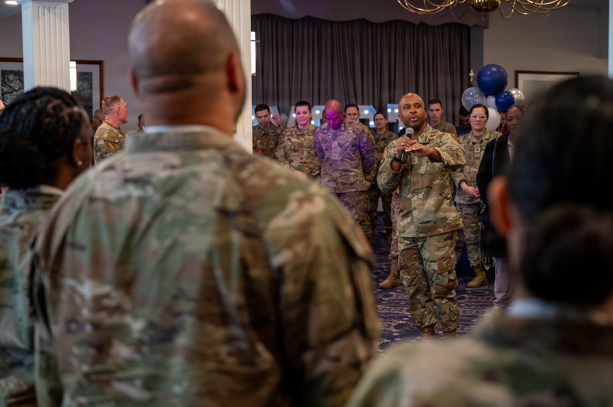 An audience member takes a photo of Senior Master Sgt. Juston Milliner, Office of Joint Chiefs of Staff, with colleagues during a chief master sergeant release party at Joint Base Anacostia-Bolling, Washington, D.C., Jan. 15, 2026. These individuals achieved the rank of chief master sergeant which is a mark of distinction, recognizing years of dedication and the ability to lead at the highest levels of the enlisted force. (U.S. Air Force photo by Hayden Hallman)
