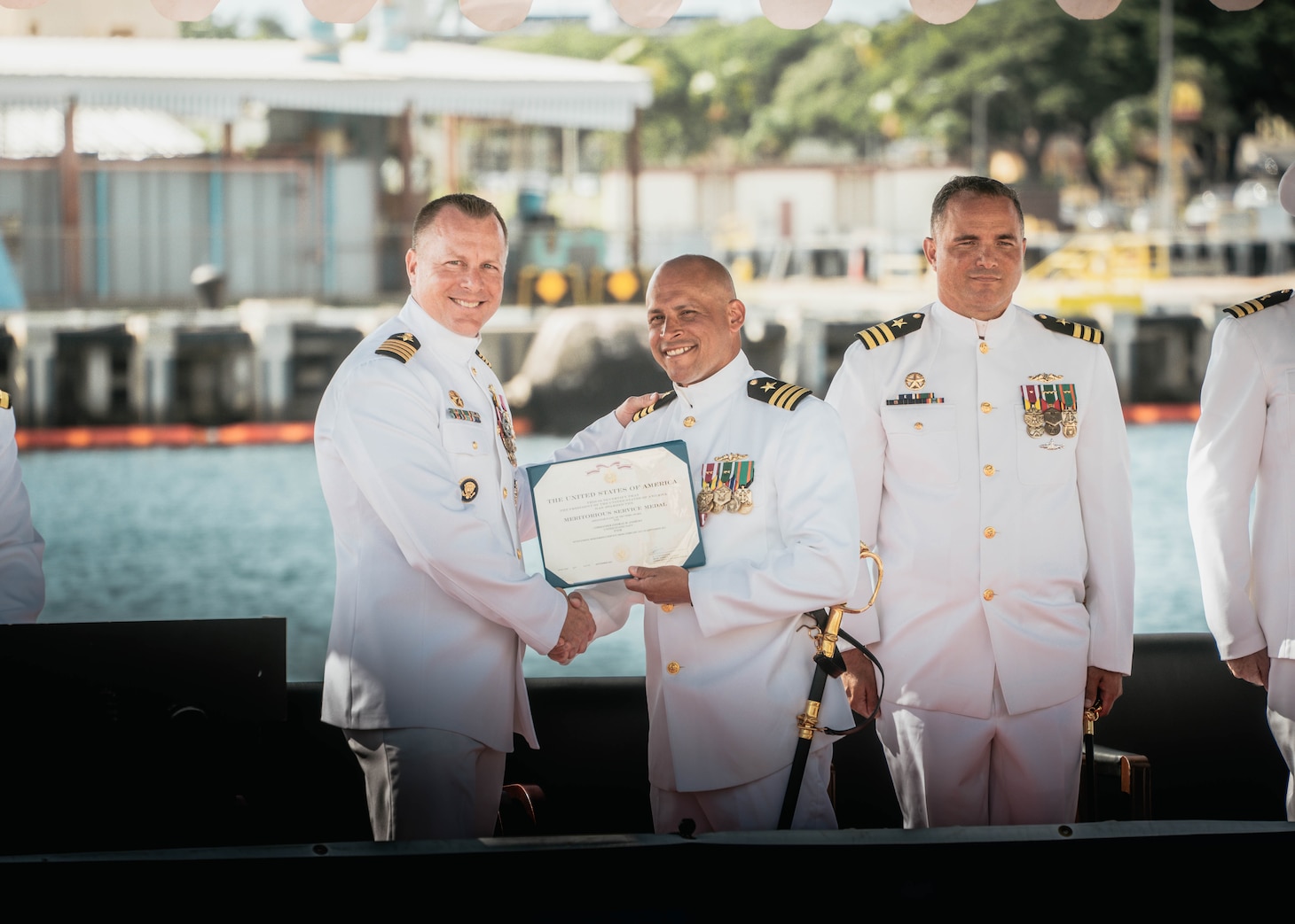 JOINT BASE PEARL HARBOR-HICKAM, Hawaii (Nov. 19, 2025) - Capt. Jeffrey Fassbender, commander, Submarine Squadron 7, left, presents Cmdr. Gieorag Andrews, outgoing commanding officer of the Virginia-class fast-attack submarine USS Missouri (SSN 780), center, with his end of tour award during the change of command ceremony for Missouri on Joint Base Pearl Harbor-Hickam, Hawaii, Nov. 19, 2025. Missouri is assigned to Submarine Squadron 7 and is capable of supporting various missions, including anti-submarine warfare, anti-surface ship warfare, strike warfare, special operations forces support, and intelligence, surveillance, and reconnaissance. (U.S. Navy photo by Mass Communication Specialist 2nd Class Nicholas Russell)