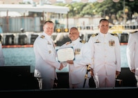 JOINT BASE PEARL HARBOR-HICKAM, Hawaii (Nov. 19, 2025) - Capt. Jeffrey Fassbender, commander, Submarine Squadron 7, left, presents Cmdr. Gieorag Andrews, outgoing commanding officer of the Virginia-class fast-attack submarine USS Missouri (SSN 780), center, with his end of tour award during the change of command ceremony for Missouri on Joint Base Pearl Harbor-Hickam, Hawaii, Nov. 19, 2025. Missouri is assigned to Submarine Squadron 7 and is capable of supporting various missions, including anti-submarine warfare, anti-surface ship warfare, strike warfare, special operations forces support, and intelligence, surveillance, and reconnaissance. (U.S. Navy photo by Mass Communication Specialist 2nd Class Nicholas Russell)