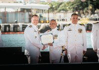 JOINT BASE PEARL HARBOR-HICKAM, Hawaii (Nov. 19, 2025) - Capt. Jeffrey Fassbender, commander, Submarine Squadron 7, left, presents Cmdr. Gieorag Andrews, outgoing commanding officer of the Virginia-class fast-attack submarine USS Missouri (SSN 780), center, with his end of tour award during the change of command ceremony for Missouri on Joint Base Pearl Harbor-Hickam, Hawaii, Nov. 19, 2025. Missouri is assigned to Submarine Squadron 7 and is capable of supporting various missions, including anti-submarine warfare, anti-surface ship warfare, strike warfare, special operations forces support, and intelligence, surveillance, and reconnaissance. (U.S. Navy photo by Mass Communication Specialist 2nd Class Nicholas Russell)