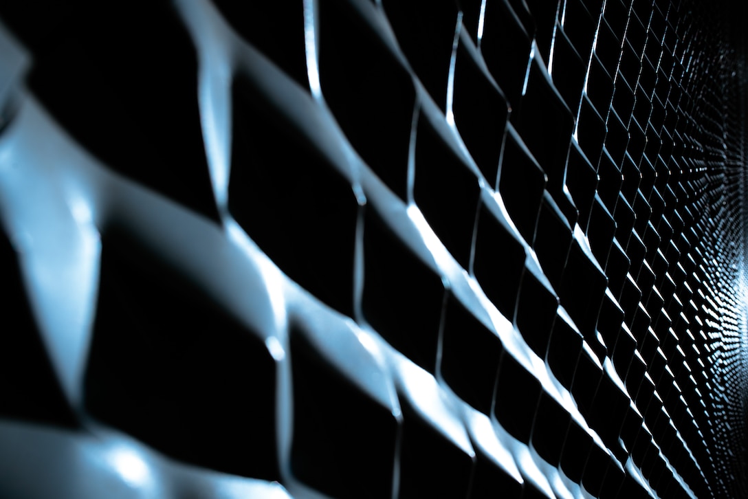 Industrial background of diagonal metallic protrusions illuminated with strong light and intense shadows.