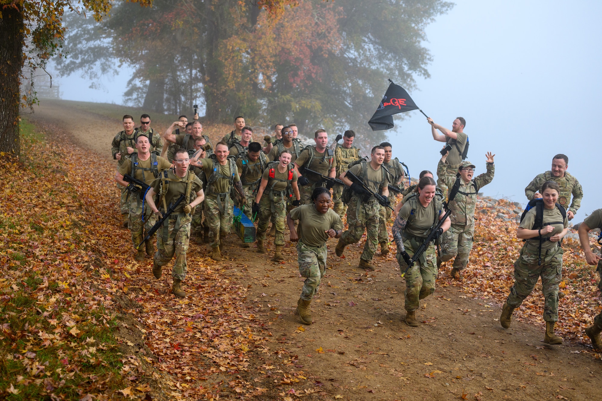 A flight of servicemembers run down a hill together, yelling and celebrating.