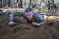 Air Force Servicemember crawls through sand for obstacle course