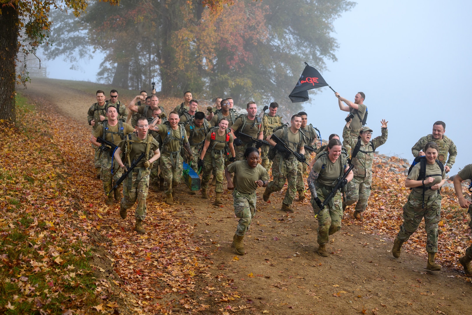 A flight of servicemembers run down a hill together, yelling and celebrating.