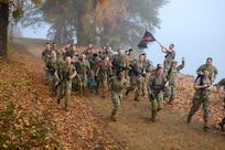 A flight of servicemembers run down a hill together, yelling and celebrating.