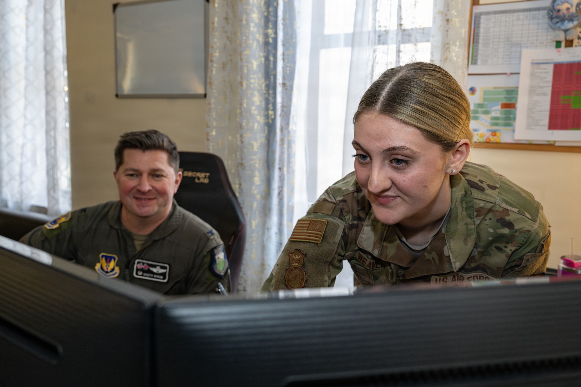 U.S. Air Force Senior Airman Kailey Weaver, right, 100th Security Forces Squadron post agency check manager, shows Col. Steven Byrum, 100th Air Refueling Wing commander, how to complete an open area access validation for a restricted area badge during a day in the life immersion at RAF Mildenhall, England, Jan. 14, 2026.