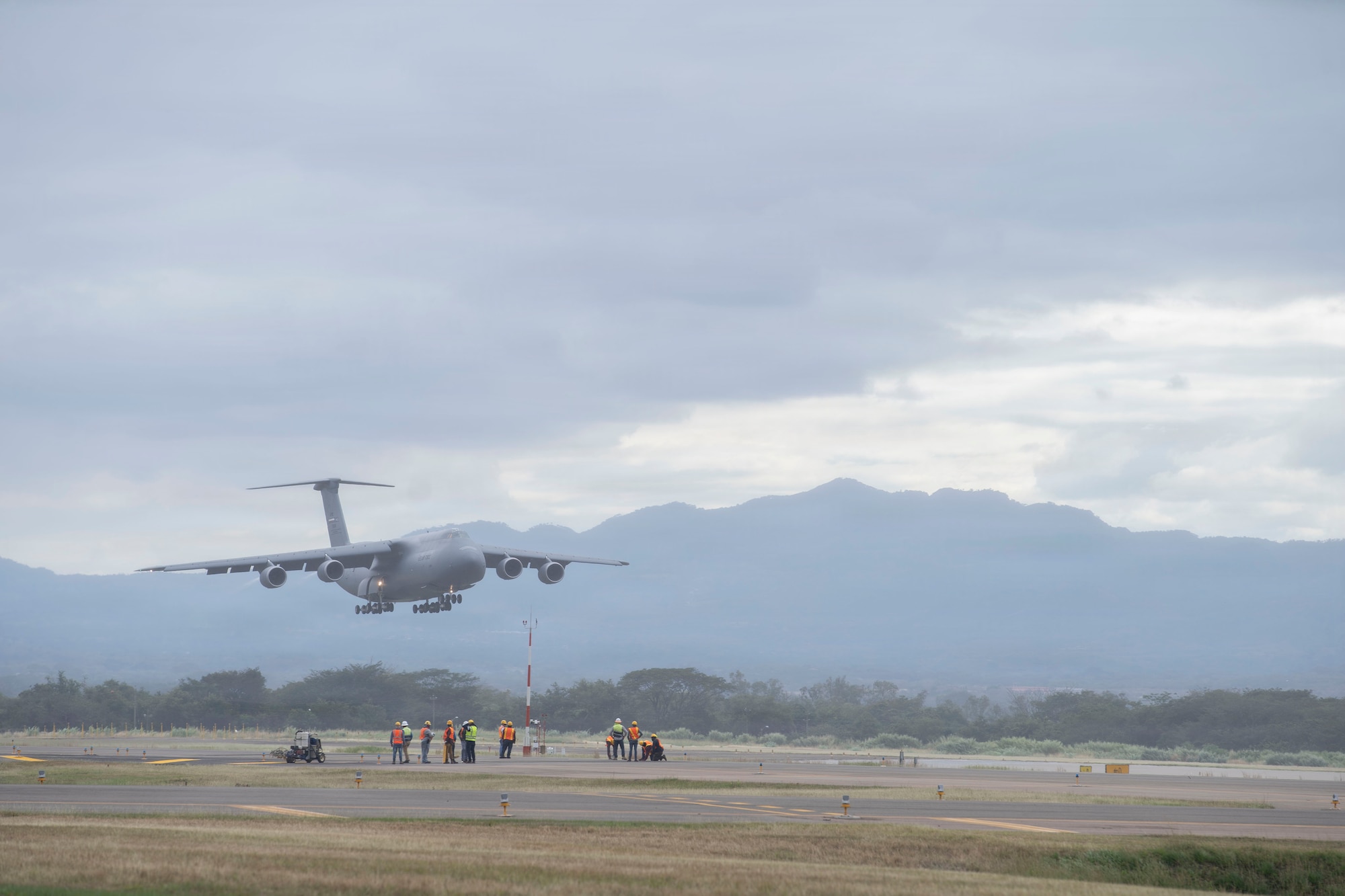 A military airplane approaches a runway to land