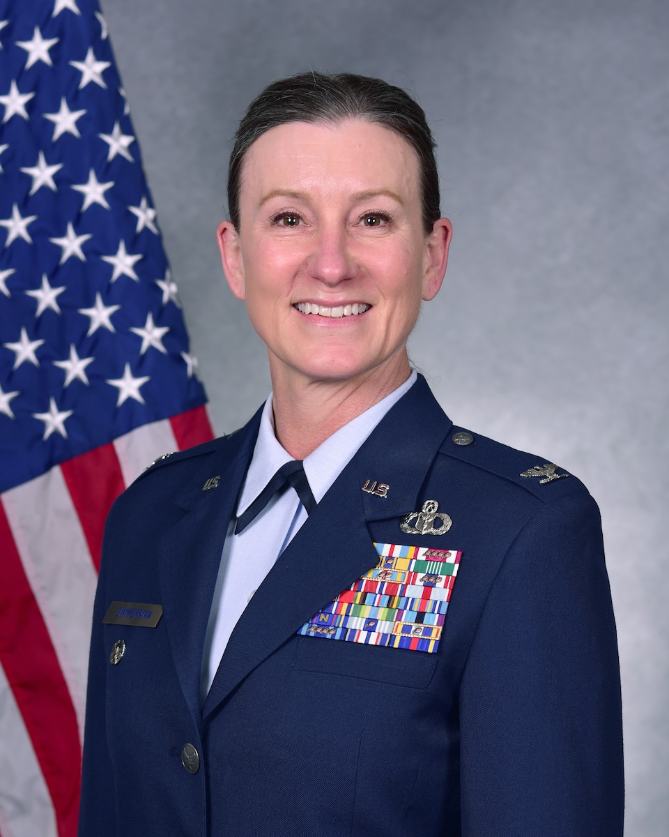 Woman in uniform poses for official photo in front of American flag