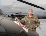 Sgt. James Gale, a crew chief with G Company, 1-189th Aviation, Oregon Army National Guard, displays the SK-1189-V litter strap at Salem's McNary Army National Guard Field Heliport, Dec. 5, 2025. The new strap, designated SK-1189-V after the Oregon unit that developed it, solves a critical equipment compatibility issue with the Vita Vertical Rescue System and will become standard equipment for all Army medevac units. Photo by Maj. W. Chris Clyne.