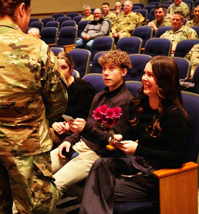 Illinois Army National Guard Chief Warrant Officer 4 Melissa Downey presents flowers to her 20-year-old daughter, Leah Hiller, and 16-year-old son, Luke Hiller, during her promotion ceremony.
