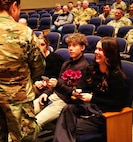 Illinois Army National Guard Chief Warrant Officer 4 Melissa Downey presents flowers to her 20-year-old daughter, Leah Hiller, and 16-year-old son, Luke Hiller, during her promotion ceremony.