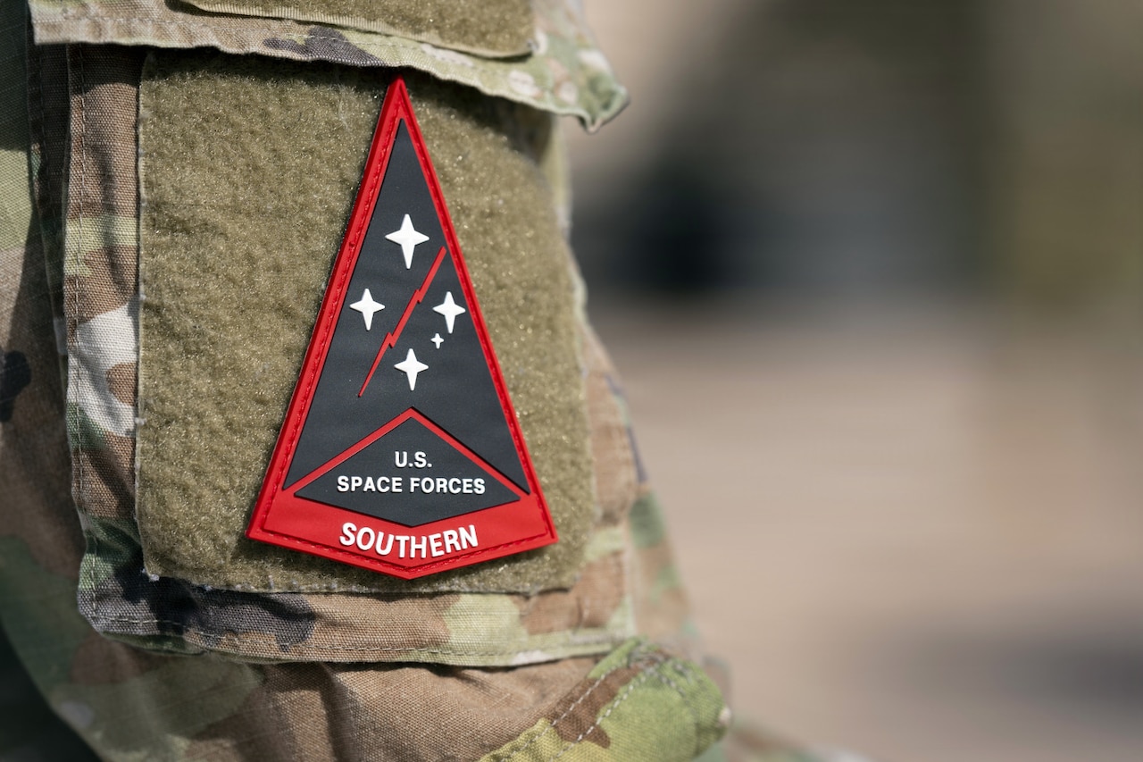 A red triangular patch with the words U.S. Space Forces Southern is shown on a camouflage military uniform.