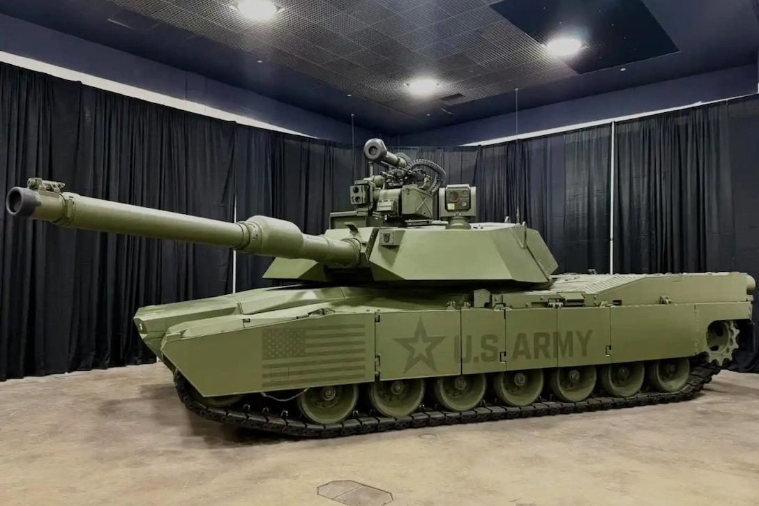 A green Army tank prototype is seen parked indoors.