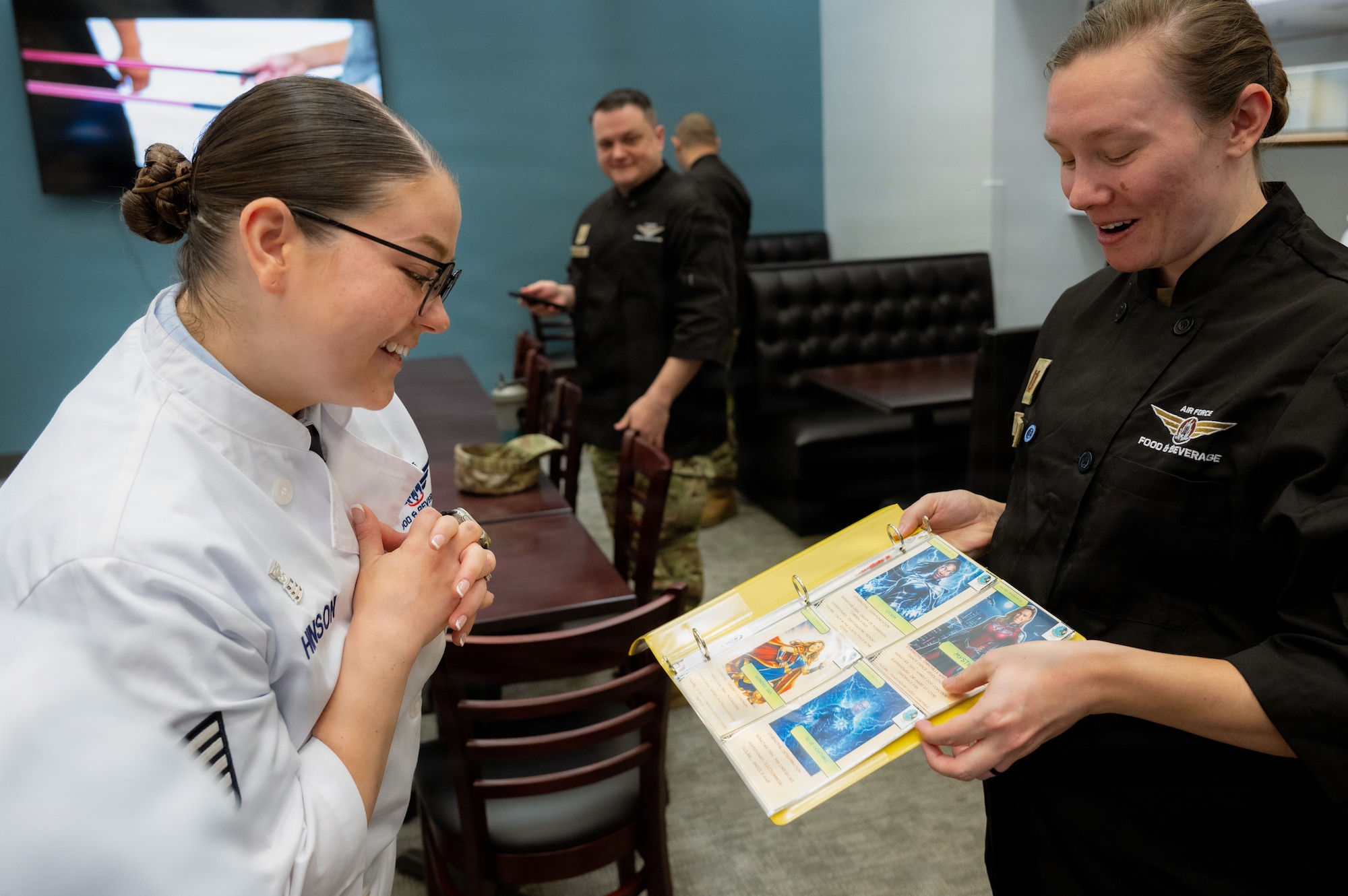 U.S. Air Force Capt. Rachel Marron, 436th Force Support Squadron Sustainment Services flight chief, displays custom super hero cards of the dining facility personnel for critics of the Hennessy Food Services awards on Dover Air Force Base, Delaware, Jan. 22, 2026.