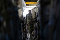 A service member walks down the cargo hold of a military airplane