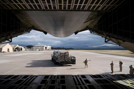 Service members offload cargo from a military airplane