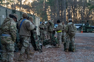A group of Airmen check equipment with equipment and storage in the background.