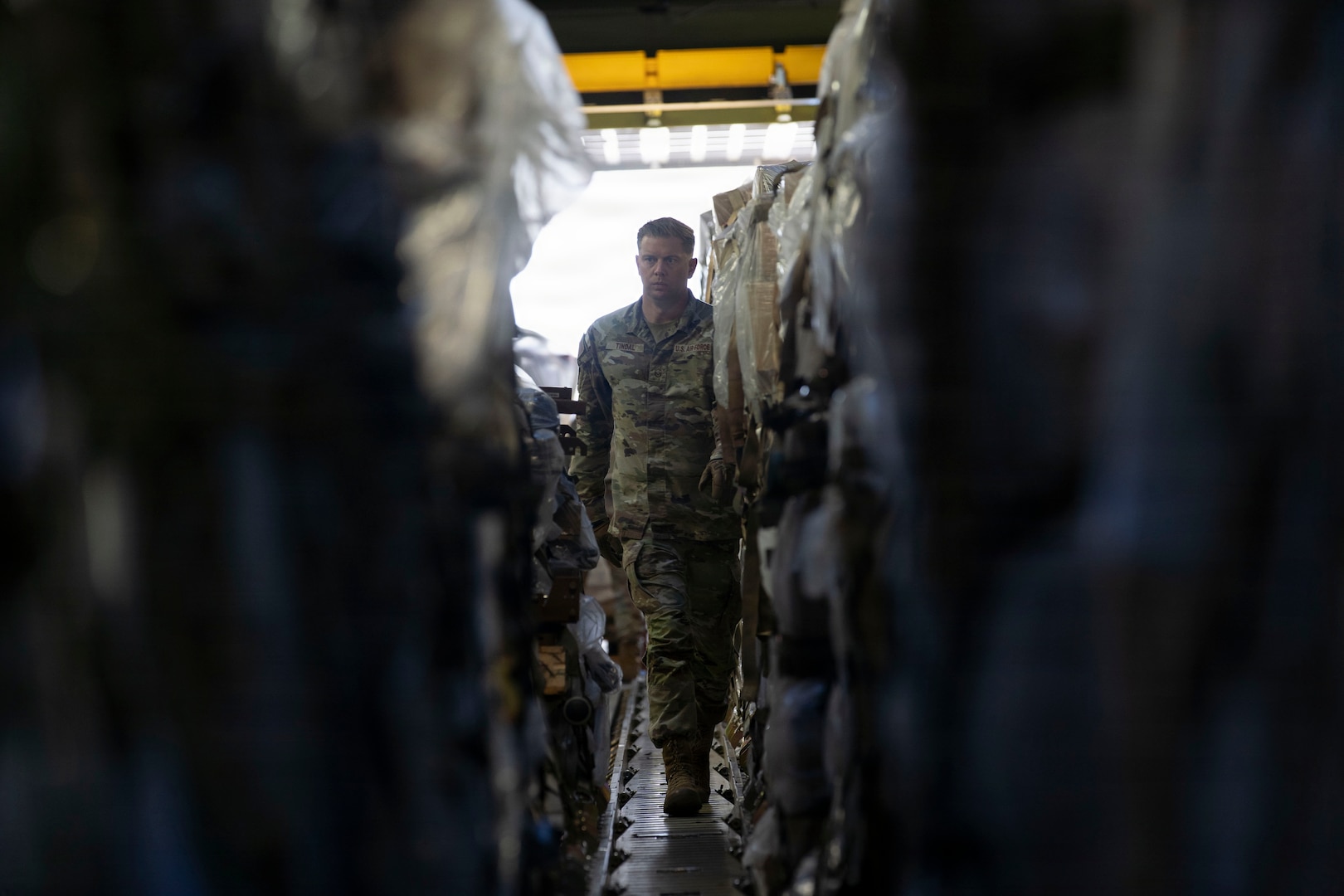 A service member walks down the cargo hold of a military airplane